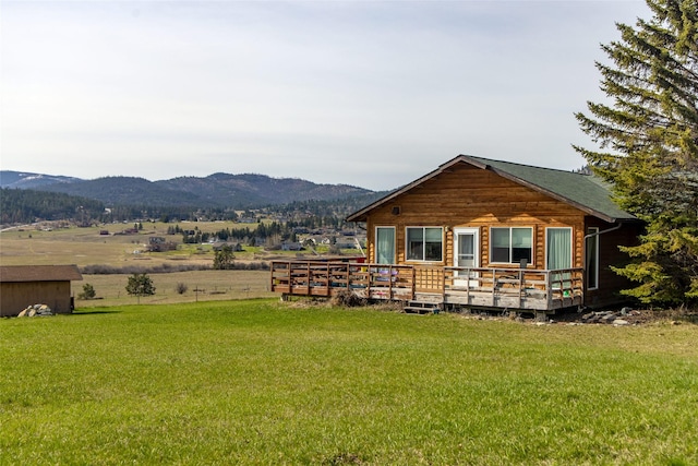 rear view of house featuring a deck with mountain view and a yard