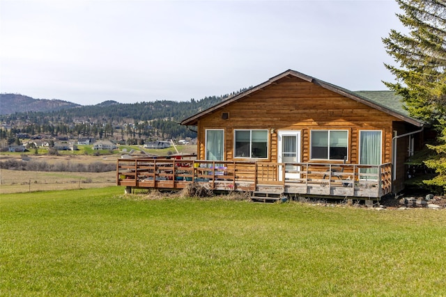 rear view of house with a yard and a deck with mountain view