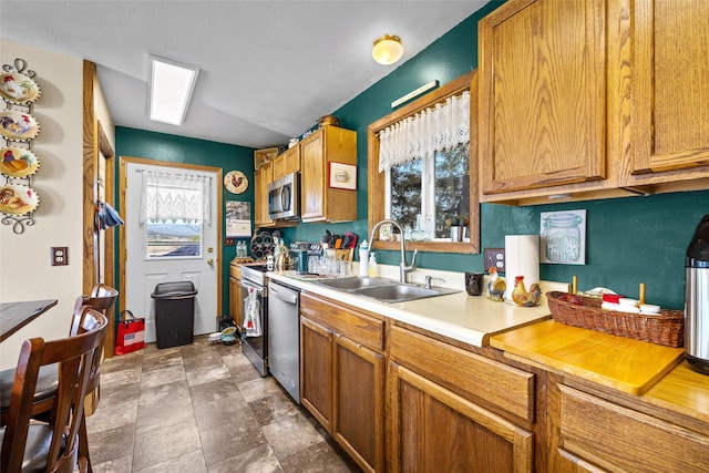 kitchen featuring light countertops, brown cabinets, appliances with stainless steel finishes, and a sink