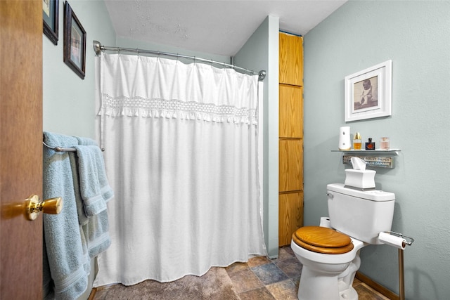 full bath featuring stone finish floor, toilet, and a shower with curtain