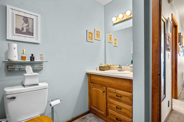 half bathroom with vanity, baseboards, and toilet