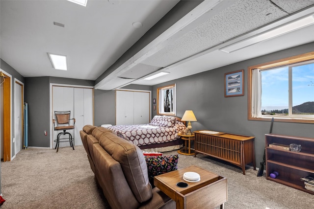 carpeted bedroom with baseboards and two closets