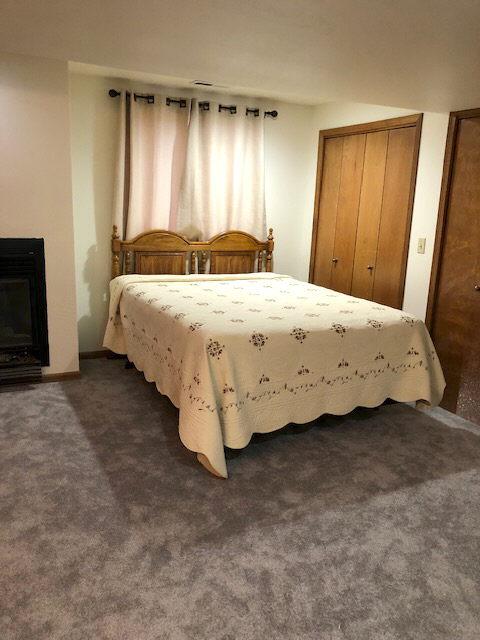 bedroom with a glass covered fireplace, two closets, and dark colored carpet