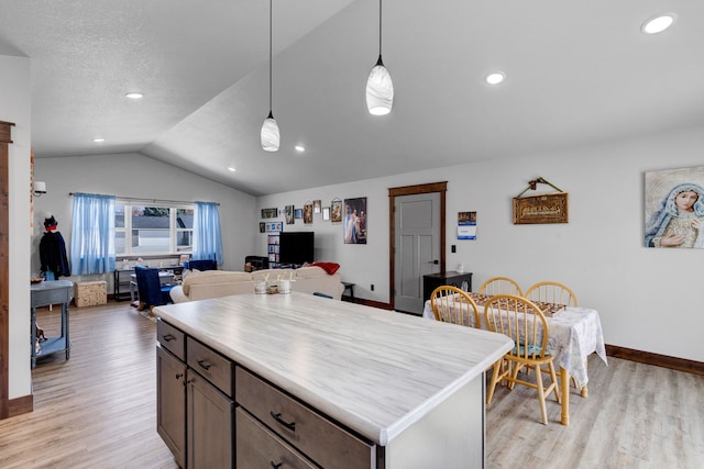kitchen with light wood-style flooring, open floor plan, baseboards, vaulted ceiling, and pendant lighting