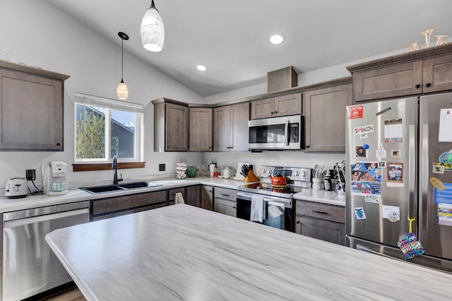 kitchen with dark brown cabinetry, hanging light fixtures, appliances with stainless steel finishes, a sink, and lofted ceiling