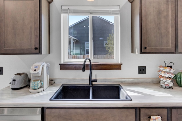 kitchen with dark brown cabinets, a sink, and dishwasher