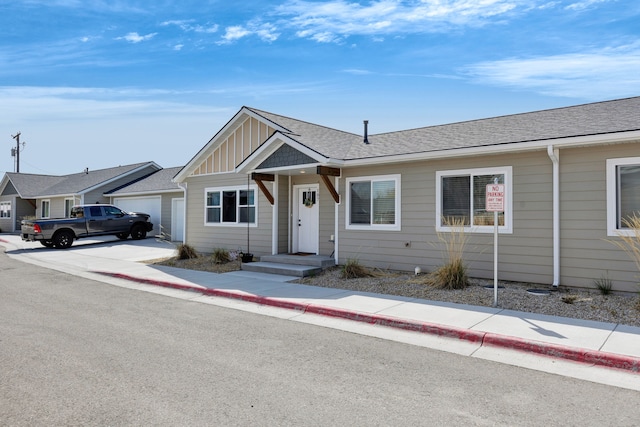 ranch-style home with an attached garage, a shingled roof, board and batten siding, and concrete driveway
