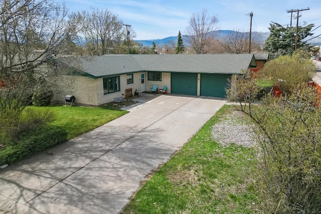 ranch-style house with a garage, roof with shingles, brick siding, concrete driveway, and a mountain view