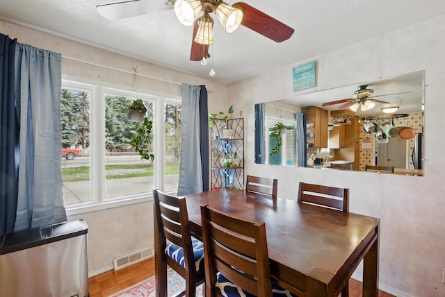 dining space with baseboards, a ceiling fan, and visible vents