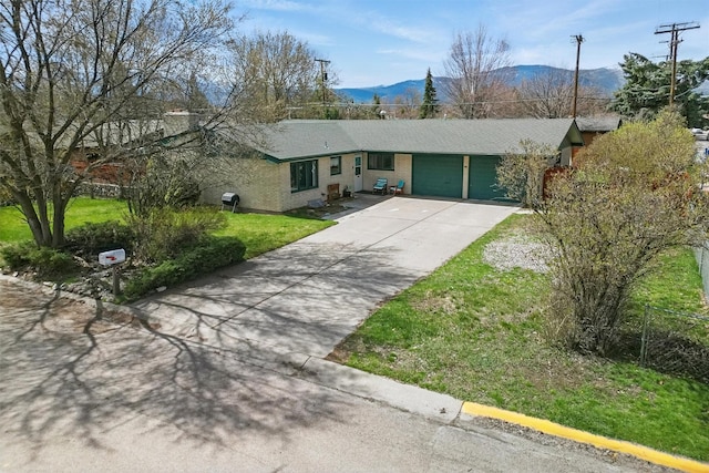ranch-style home with a front yard, brick siding, an attached garage, a mountain view, and driveway