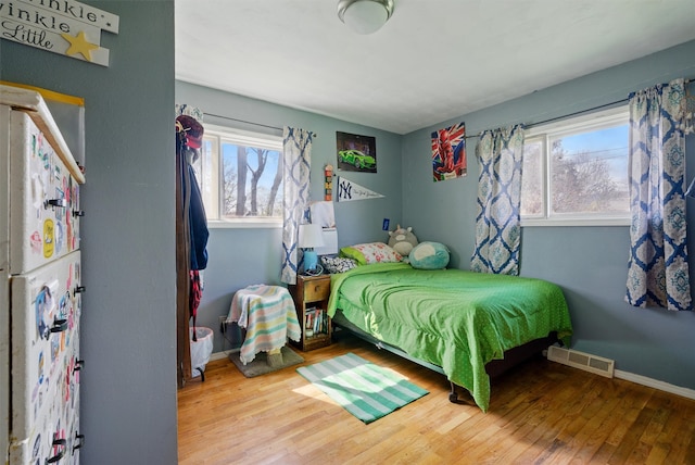 bedroom with baseboards, visible vents, and wood finished floors