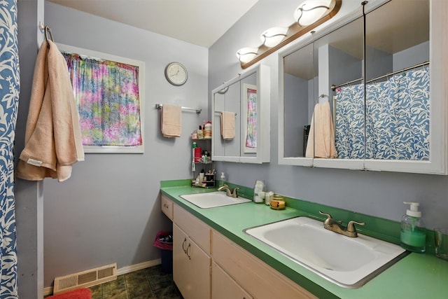 full bath featuring a sink, baseboards, double vanity, and visible vents