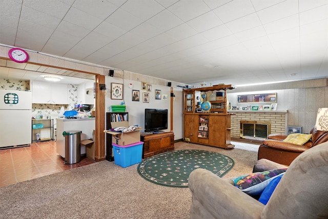 living room featuring carpet floors, wood walls, and a brick fireplace