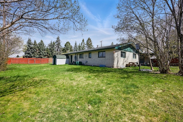 rear view of property featuring fence, an outbuilding, a yard, and a shed