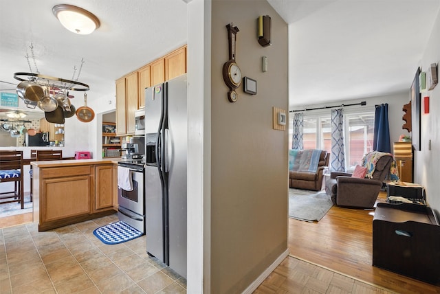 kitchen featuring an inviting chandelier, a peninsula, open floor plan, light countertops, and appliances with stainless steel finishes