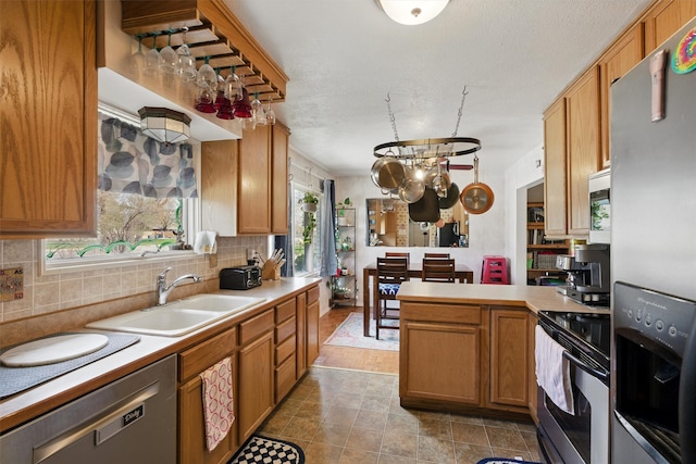 kitchen featuring light countertops, appliances with stainless steel finishes, a sink, and tasteful backsplash