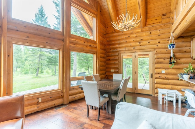 dining area featuring a notable chandelier, high vaulted ceiling, hardwood / wood-style floors, wooden ceiling, and a wealth of natural light