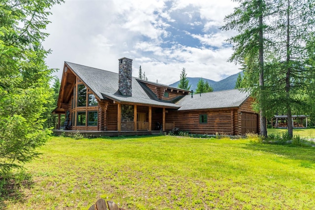 rear view of property featuring a yard, a garage, log siding, and a chimney