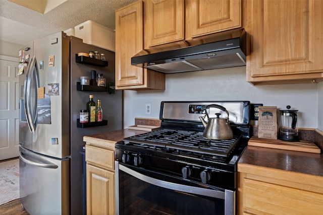 kitchen with under cabinet range hood, stainless steel appliances, and dark countertops