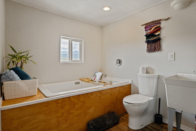bathroom with vanity, a tub with jets, toilet, and wood finished floors