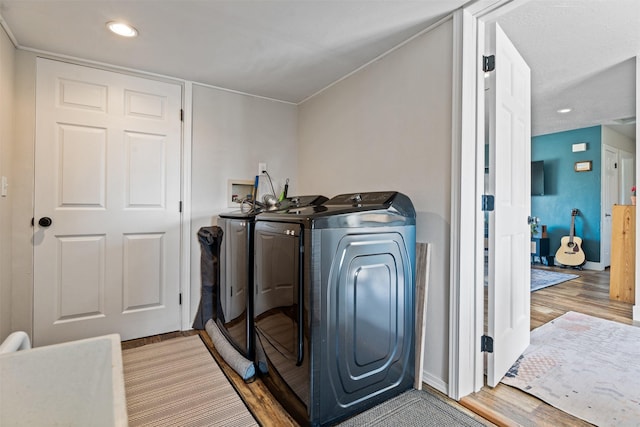 clothes washing area featuring laundry area, wood finished floors, baseboards, separate washer and dryer, and recessed lighting