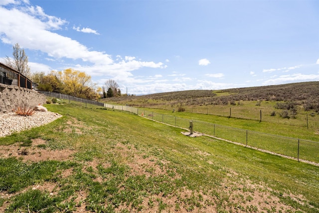 view of yard with fence and a rural view