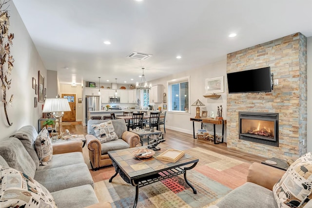 living room with light wood finished floors, a fireplace, recessed lighting, baseboards, and visible vents