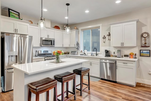 kitchen featuring white cabinets, a sink, a kitchen breakfast bar, stainless steel appliances, and tasteful backsplash