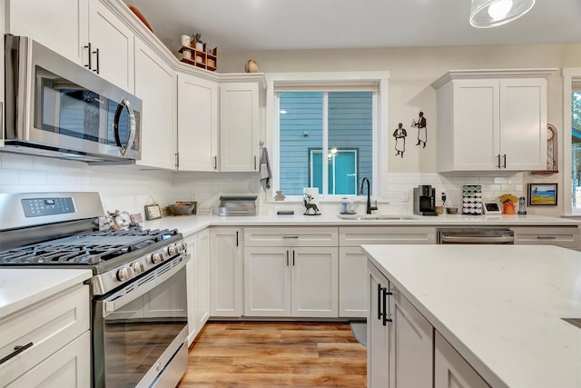 kitchen featuring light countertops, white cabinetry, a sink, backsplash, and stainless steel appliances