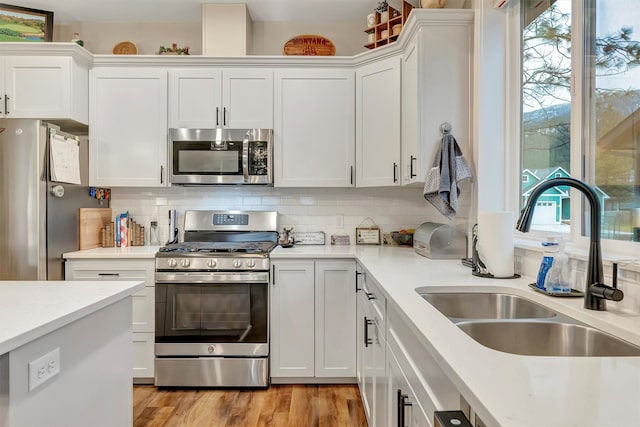 kitchen featuring a sink, light countertops, stainless steel appliances, and white cabinetry