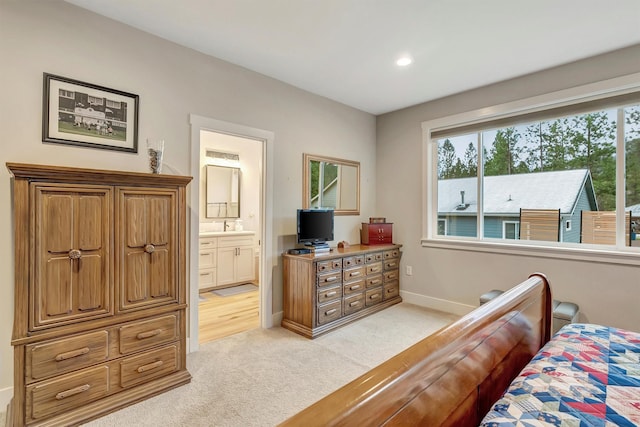bedroom featuring baseboards, ensuite bathroom, light colored carpet, recessed lighting, and a sink