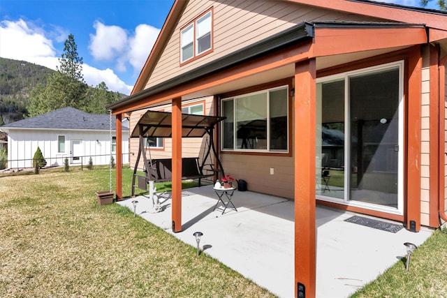 back of property with a yard, fence, a mountain view, and a patio area