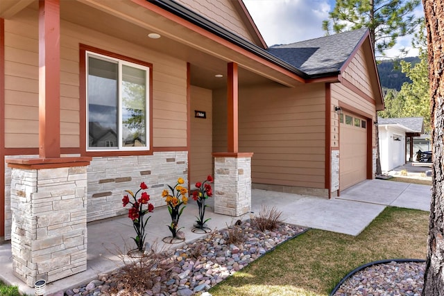 view of exterior entry featuring a garage, roof with shingles, and stone siding