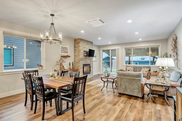 dining room with recessed lighting, an inviting chandelier, light wood-type flooring, and a fireplace