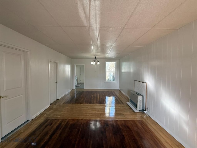 interior space with an inviting chandelier, heating unit, wood-type flooring, and baseboards
