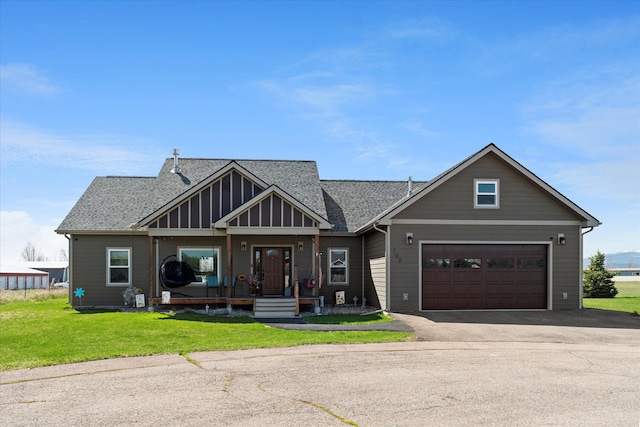 craftsman inspired home featuring covered porch, roof with shingles, driveway, and a front yard