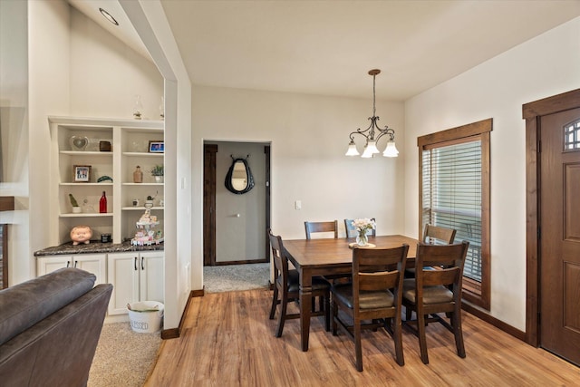 dining room featuring baseboards, light wood-type flooring, and a notable chandelier