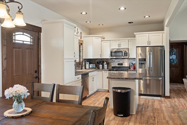 kitchen featuring a center island, light wood-type flooring, a sink, backsplash, and stainless steel appliances