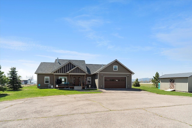 craftsman-style house with a garage, a front lawn, aphalt driveway, roof with shingles, and board and batten siding