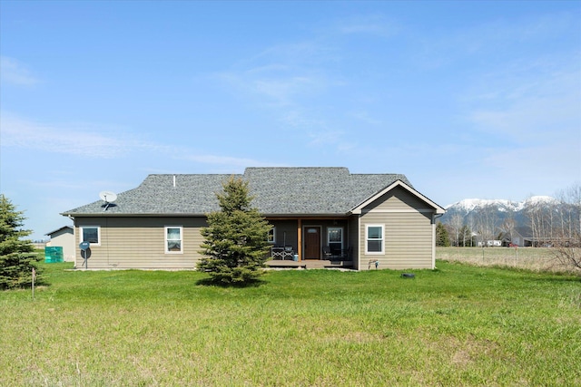 back of house with a lawn and a mountain view