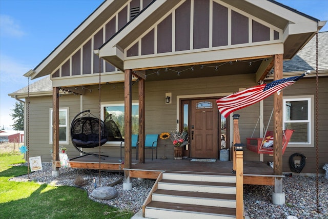 view of exterior entry featuring a shingled roof and covered porch