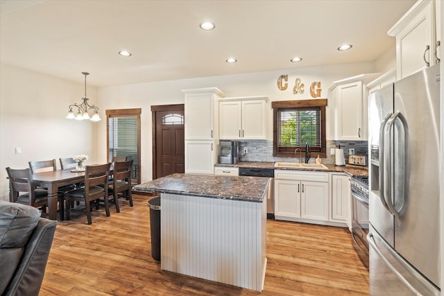kitchen with a center island, tasteful backsplash, a sink, stainless steel appliances, and white cabinetry