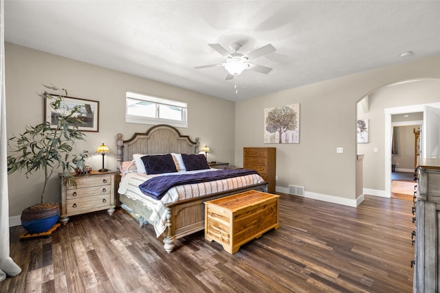 bedroom with visible vents, baseboards, ceiling fan, dark wood-type flooring, and arched walkways