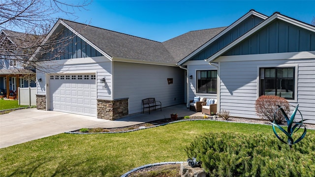 view of front of home with board and batten siding, a front lawn, roof with shingles, and a garage