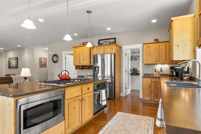kitchen with dark wood-style flooring, dark countertops, a sink, a center island, and stainless steel appliances