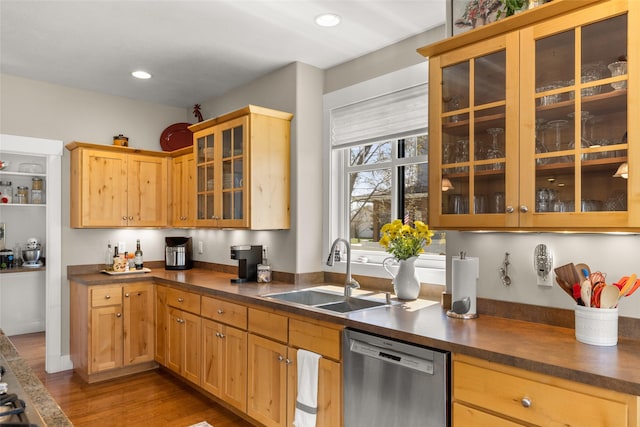 kitchen with wood finished floors, dark countertops, glass insert cabinets, a sink, and dishwasher