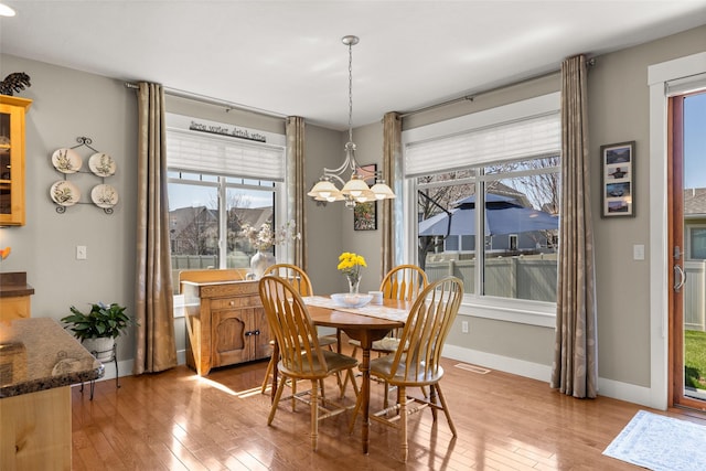 dining space featuring baseboards, a notable chandelier, hardwood / wood-style flooring, and visible vents