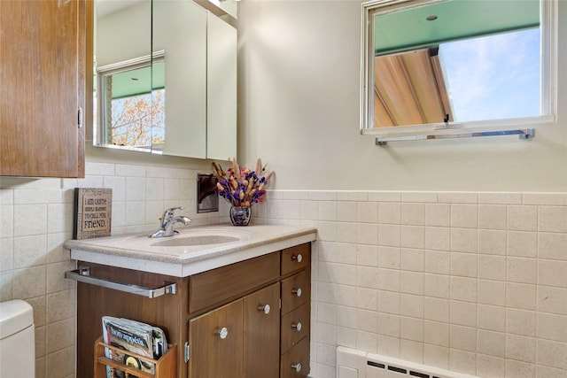 bathroom with toilet, tile walls, a wealth of natural light, and vanity