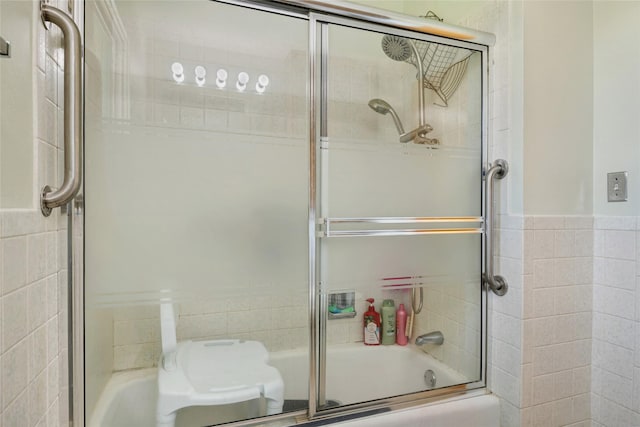 full bathroom with tile walls, wainscoting, toilet, and shower / bath combination with glass door