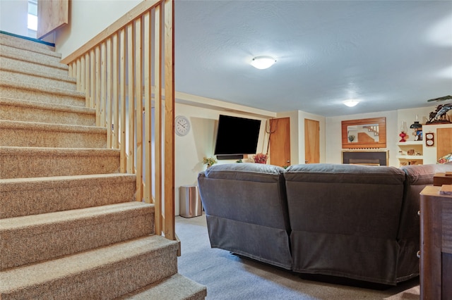 living area with carpet, stairs, and a fireplace